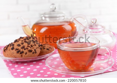 Teapot and cup of tea on table on brick wall background