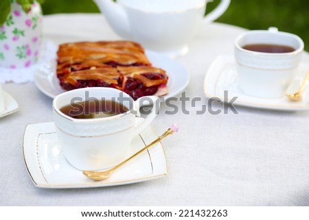 Teacups and tasty pie on table, close-up, in garden