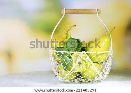 Ripe tasty pears in metal basket, on table, on nature background