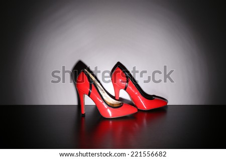 Pair of woman\'s red shoes on floor on light wall background