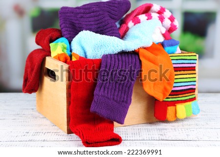 Multicoloured socks in a box on a wooden table in front of the window
