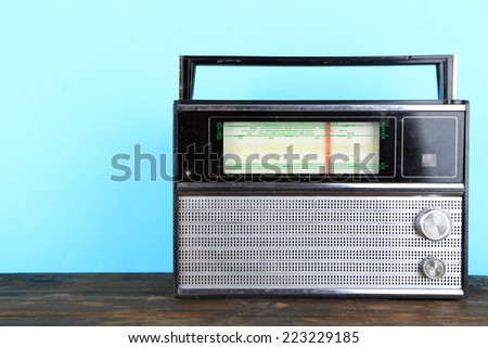 Old radio set on wooden table on blue background