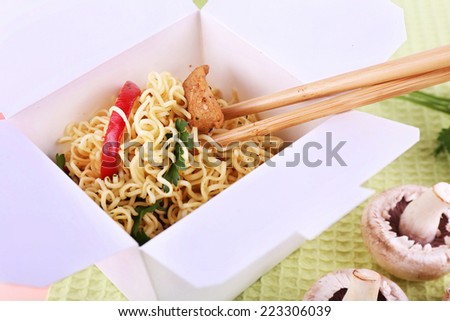 Chinese noodles in takeaway box on fabric background
