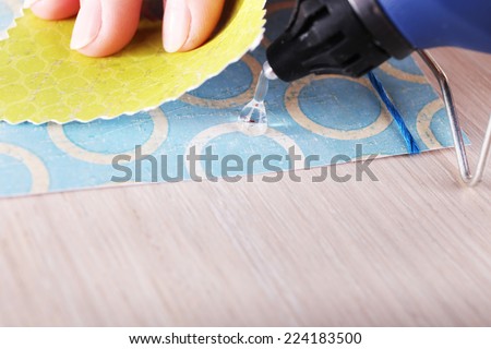 Woman\'s hand making postcard with a help of glue gun