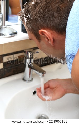 Man spraying water on his face after shaving in bathroom at home