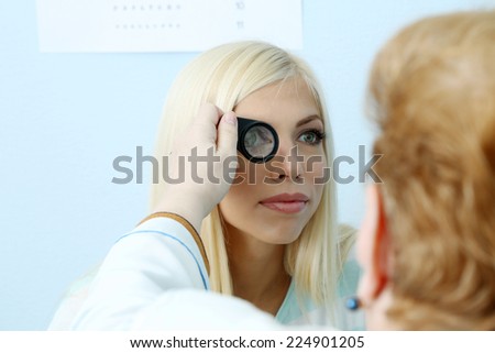 Optometry concept - pretty young woman having her eyes examined by eye doctor