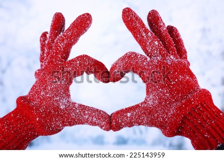Woman's hands in red gloves on winter natural background