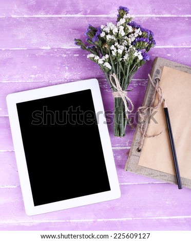 Tablet, notebook, pencil and bunch of field flowers on wooden background