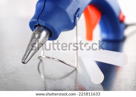 Dark blue glue gun and silicone stick on light background