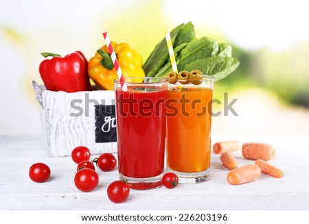 Vegetable juice and fresh vegetables in wooden box on wooden table on natural background