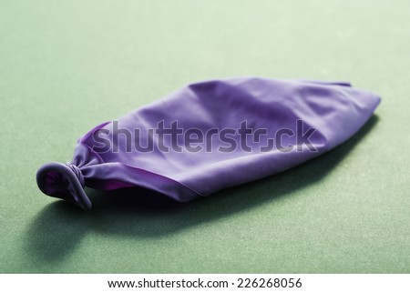Popped violet balloon on paper background