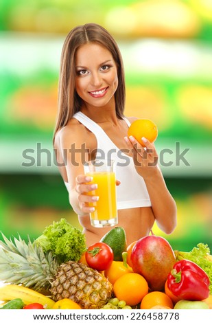 Shopping concept. Beautiful young woman with fruits and vegetables and glass of juice on shop background