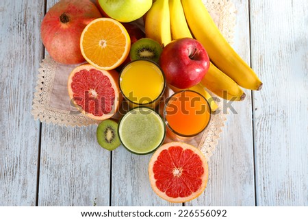 Fruit and vegetable juice and fresh fruits on napkin on wooden background