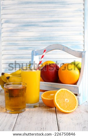 Orange and apple juice and fresh fruits in wooden box on wooden table on wooden wall background