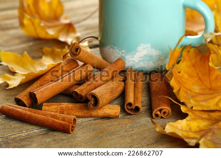 Cinnamon sticks with yellow leaves on wooden background