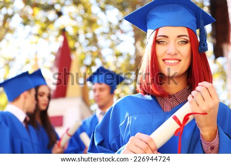Graduate students wearing graduation hat and gown, outdoors