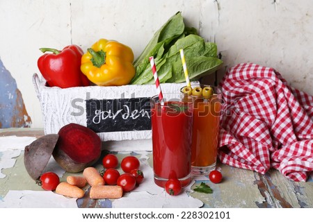 Vegetable juice and fresh vegetables in wooden box on wooden table on wall background