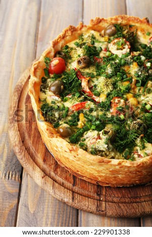 Vegetable pie with broccoli, peas, tomatoes and cheese on wooden background
