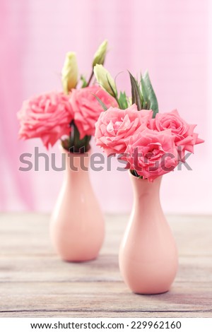Beautiful flowers in vases on table on curtains background