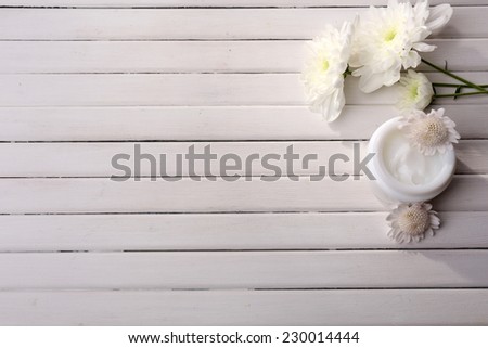 Beautiful flowers and skin cream on wooden background