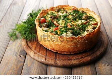 Vegetable pie with broccoli, peas, tomatoes and cheese on wooden background