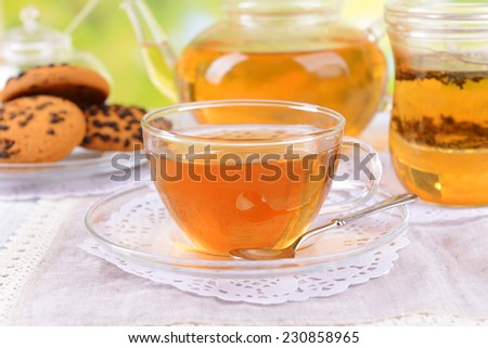 Teapot and cups of tea on table on bright background