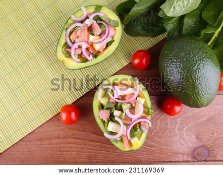 Tasty salad in avocado on table and bamboo napkin close-up