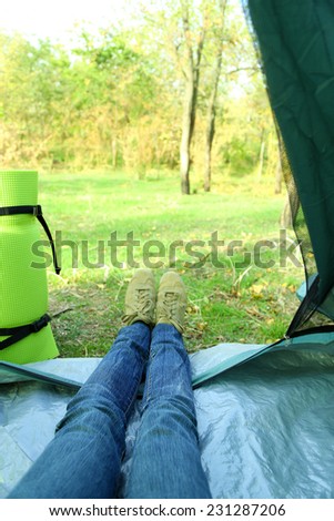 Legs lying in tourist tent in a forest