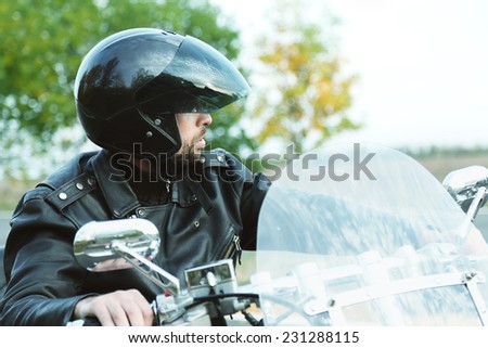 Biker man in black helmet sits on bike