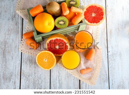 Fruit and vegetable juice and fresh vegetables and fruits on napkin and in wooden box on wooden background