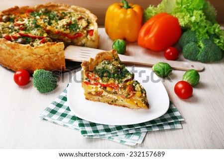Piece of Vegetable pie with broccoli, peas, tomatoes and cheese on plate, on wooden background