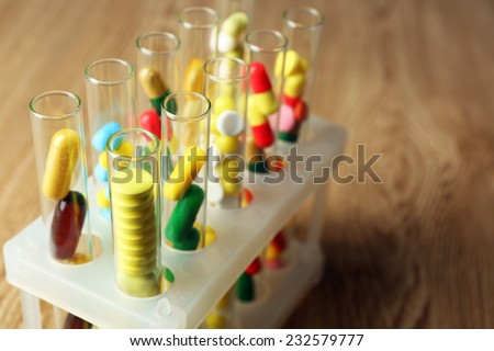Different color drugs in test tubes, on wooden table background