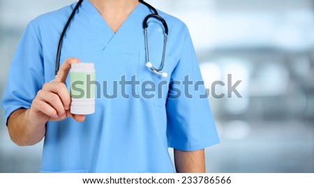 Young male doctor with pills on hospital background