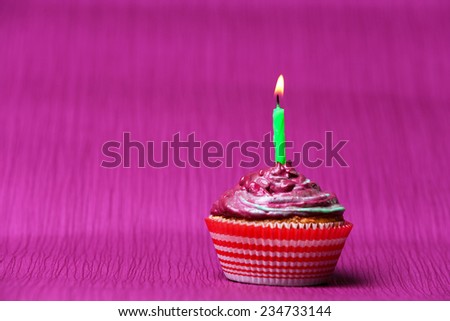 Delicious birthday cupcake on purple background