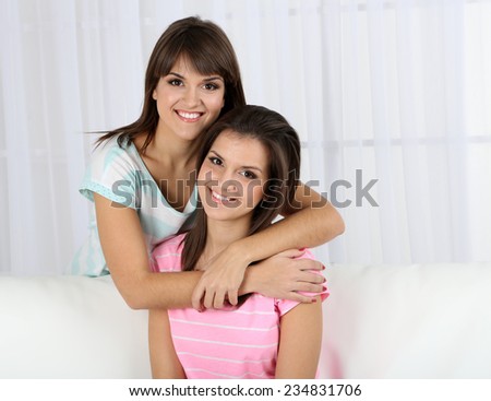 Beautiful girls twins sitting on sofa in room