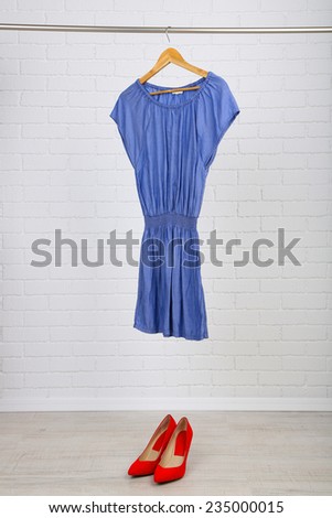 Female dress on hanger and shoes in room