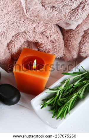 Branches of rosemary  towels, candle, spa stones on color wooden background. Rosemary spa concept
