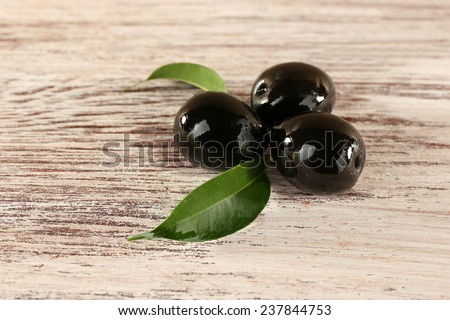Tree black olives with leaf on painted wooden background