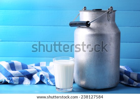 Retro can for milk and milk glass on color wooden background