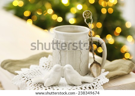 Mug with hot drink and Christmas decorations on fir tree background