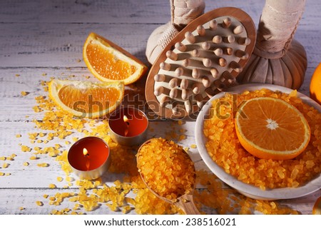 Accessories for massage therapy with candle light and bowl of bath salt on color wooden background