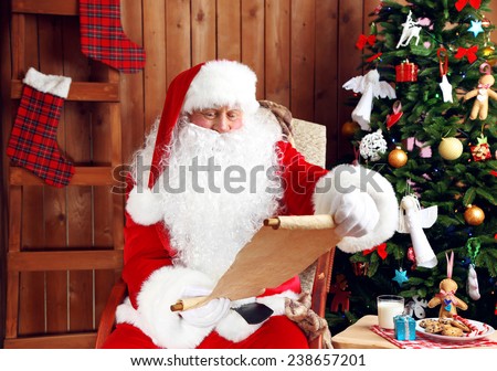 Santa Claus with list of presents sitting in comfortable rocking chair near Christmas at home