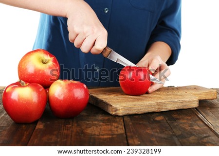 Hands of women cutting apples on board on wooden table, on white background