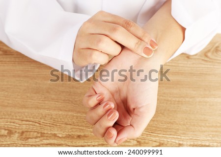 Taking heart rate oneself by hand, on wooden table background