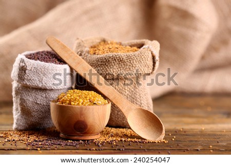 Mustard seeds in bags and sauce in bowl on  wooden background