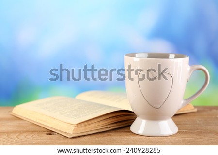 Cup of tea and book on table, on bright background