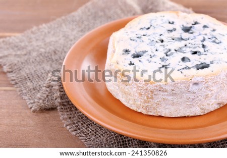 Blue cheese on earthenware dish on burlap cloth and wooden table background