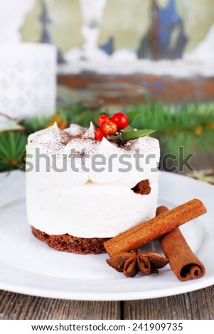 Delicious cake on plate with cinnamon and star anise on Christmas decoration background