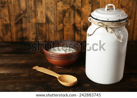 Milk can with cream on rustic wooden background