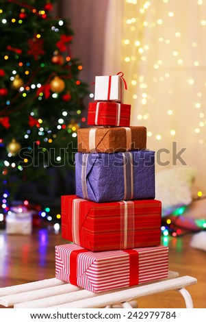 Present boxes on sledge on wooden floor near Christmas tree, indoors